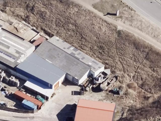 2 bygninger med 2 store portåbninger. Højloftet lagerplads med stor løbekran. 2 værkstedsrum, kontor, toilet m.m