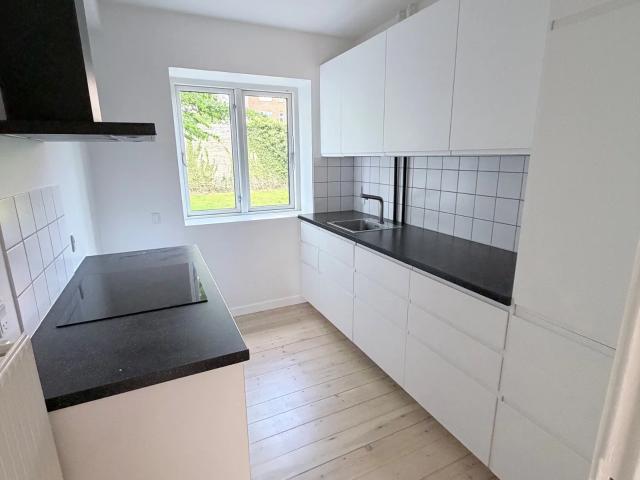 Lys og gennemmoderniseret 2 værelses på 55 m2 – indflytningsklar med stilrent køkken og charmerende detaljer