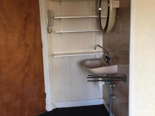 Ruime zonnige kamer met wastafel, koelkast